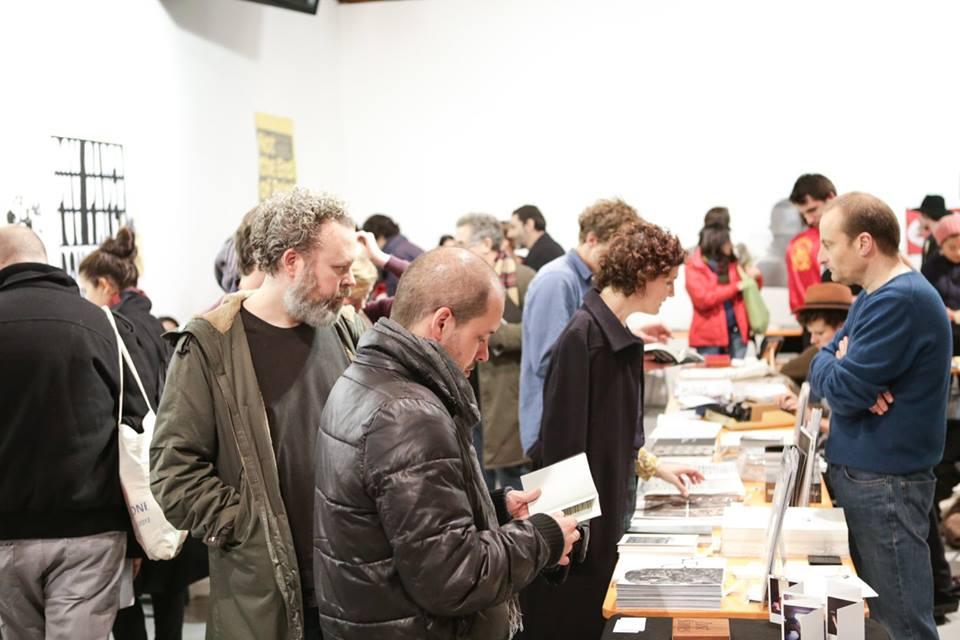 Room full of people, looking at book stands