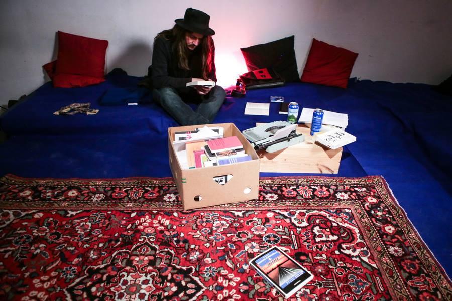 Guy sitting on a carpet with a box of books