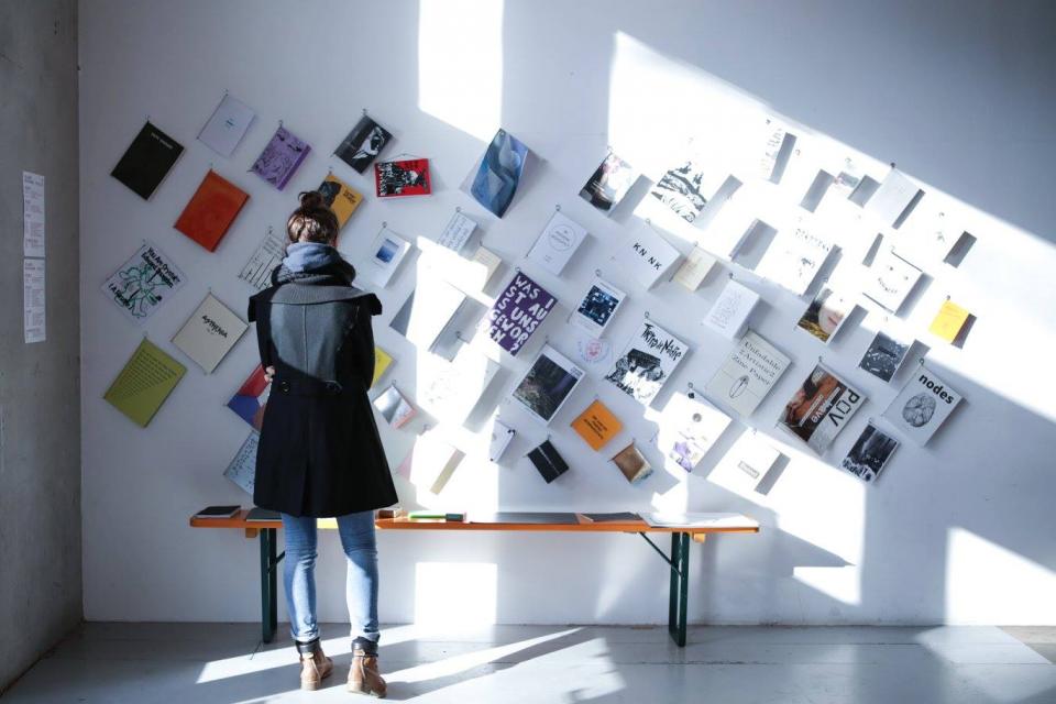 Girl standing in front of a wall with exhibited publications