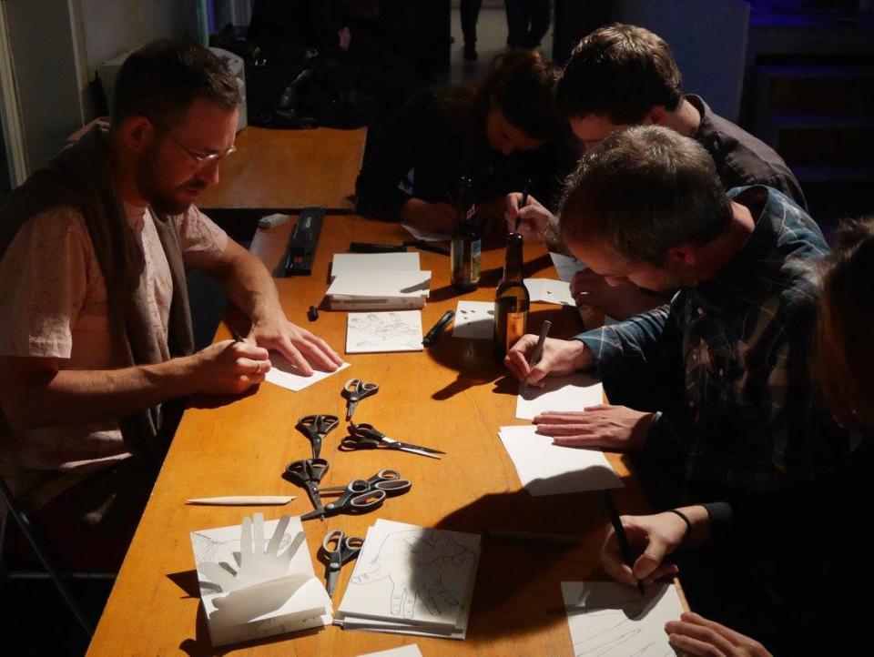 People sitting together at a table, making zines